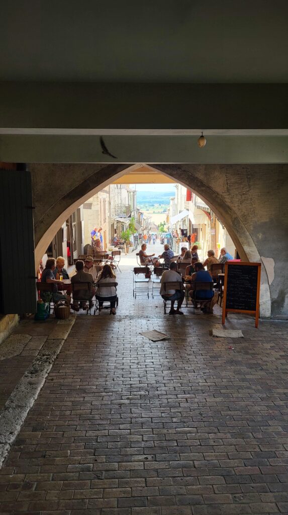 Couples and friends enjoying a quiet afternoon at a sunlit café in the charming village of Monflanquin, southwest France.