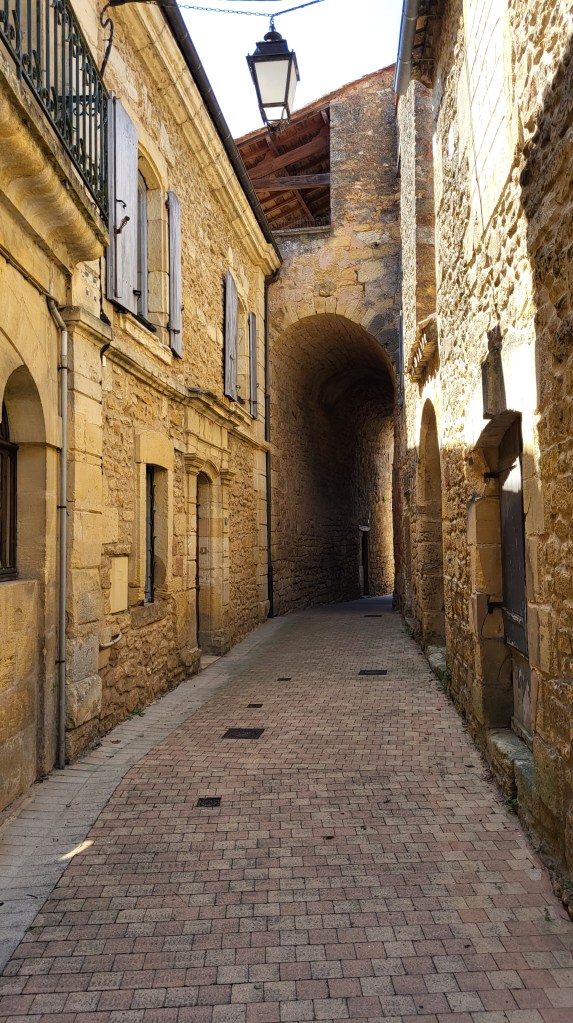 Medieval stone archway in Belvès catching late June sunlight